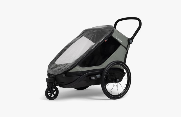 Grå og svart sykkelvogn/barnevogn med regntrekk, tre hjul og et håndtak.