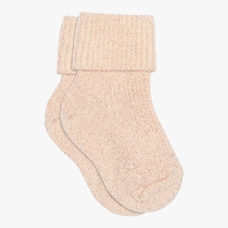 Et par lysebeige strikkede babysokker med brettede mansjetter.