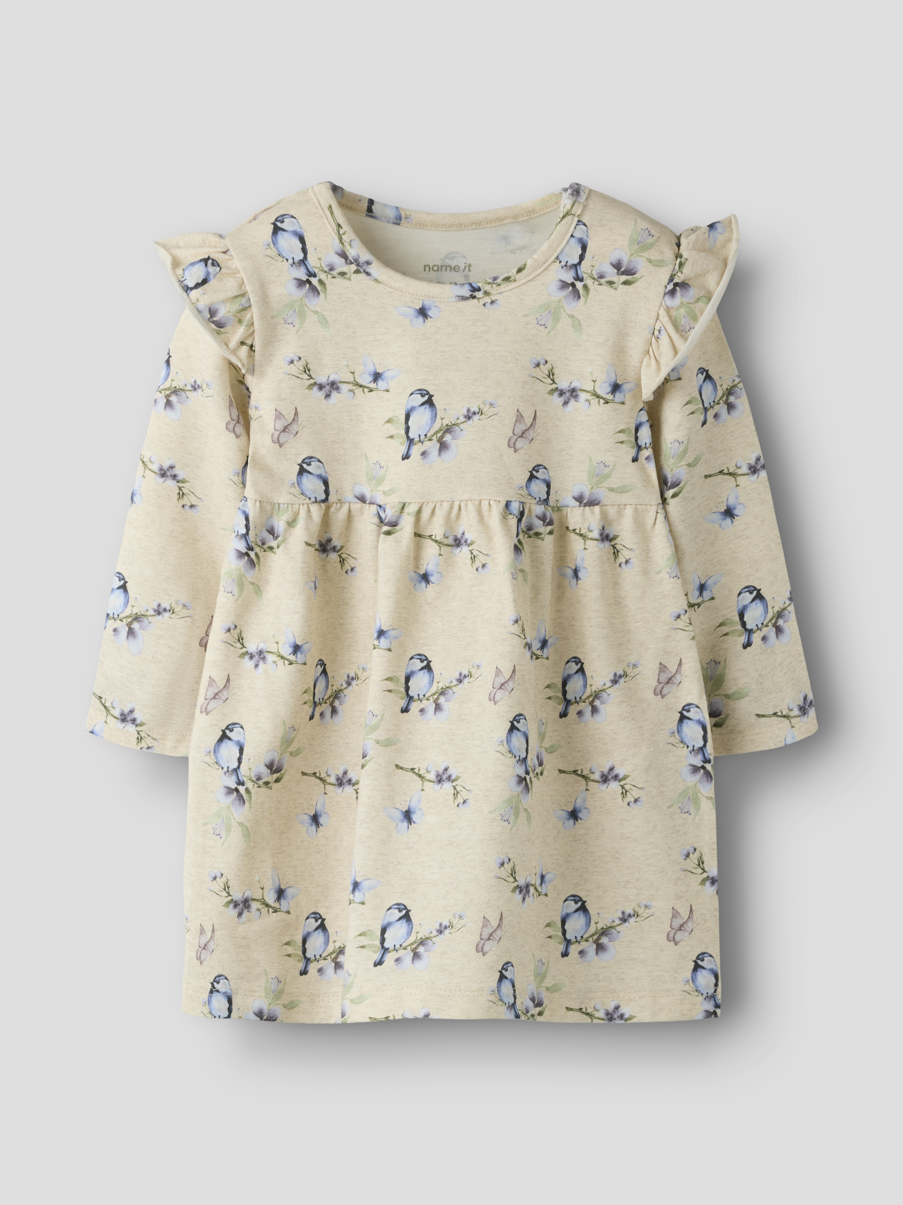 Barnekjole i beige med lange ermer, fugle- og blomstermønster, volangdetaljer på skuldrene og rynket midje.