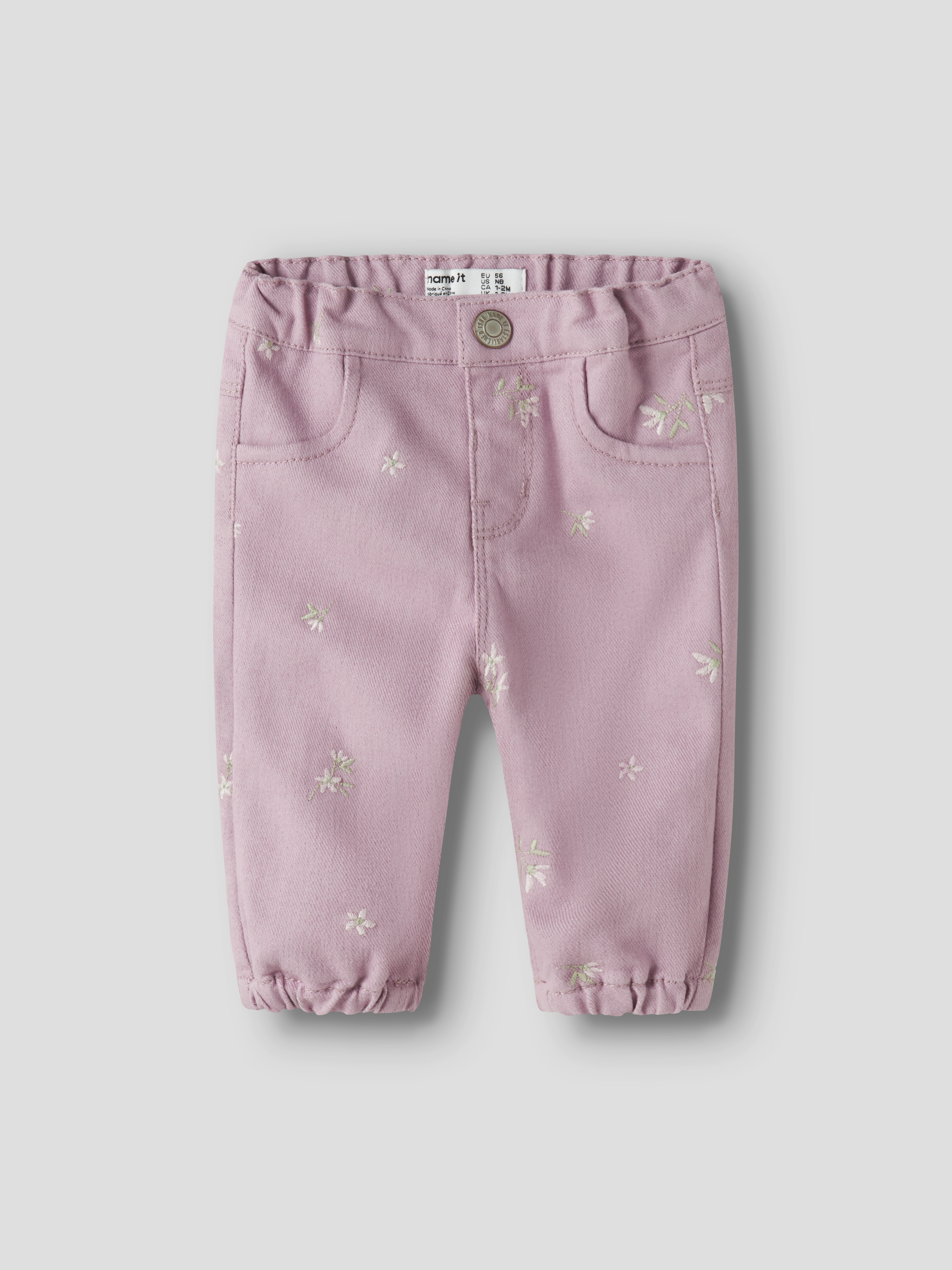 Babypikebukser i rosa med små blomsterbroderier, elastisk midje og nederkanter, og frontlommer.