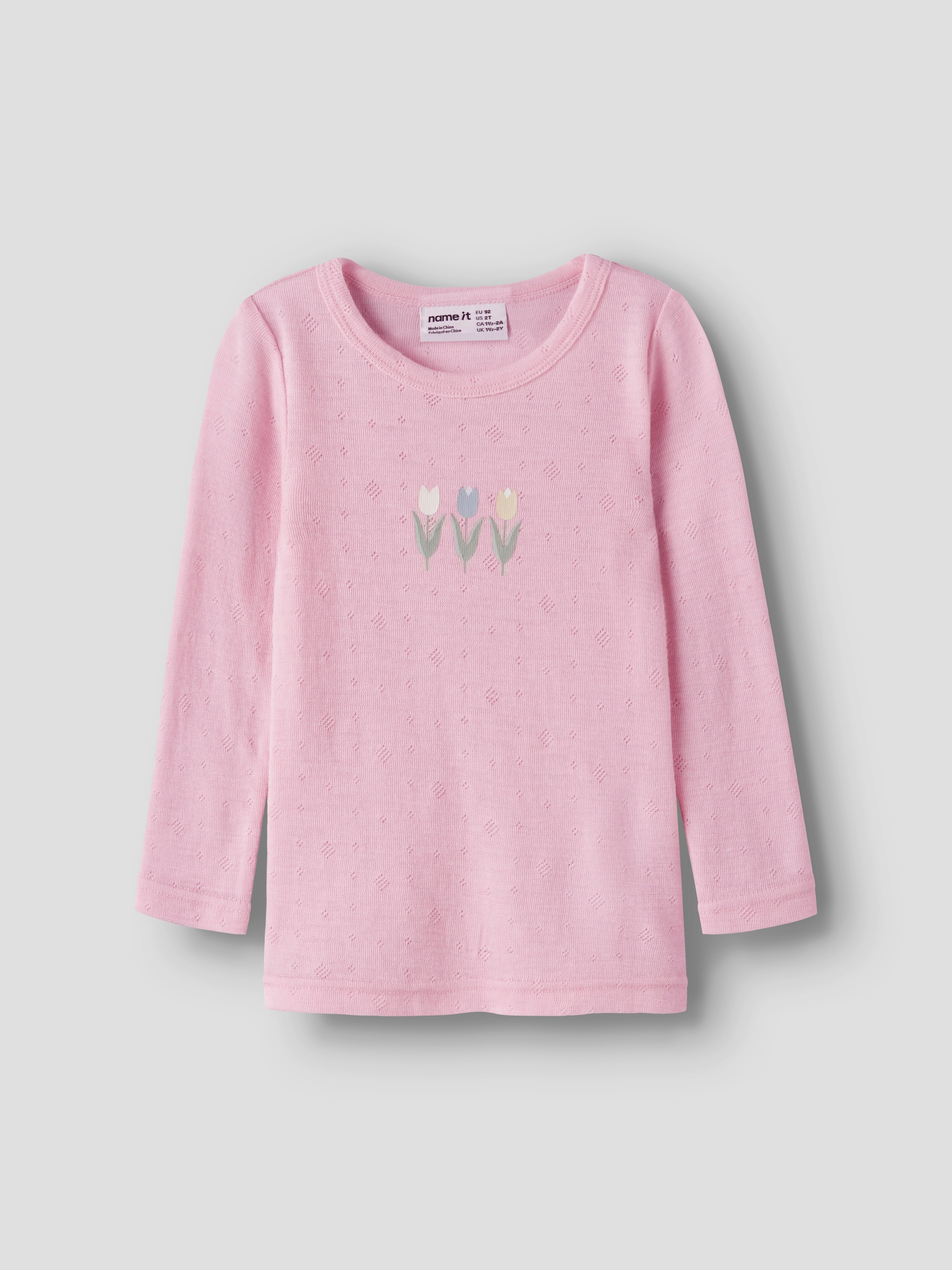En rosa langermet barnetopp med teksturerte prikker og tre broderte tulipaner på brystet.