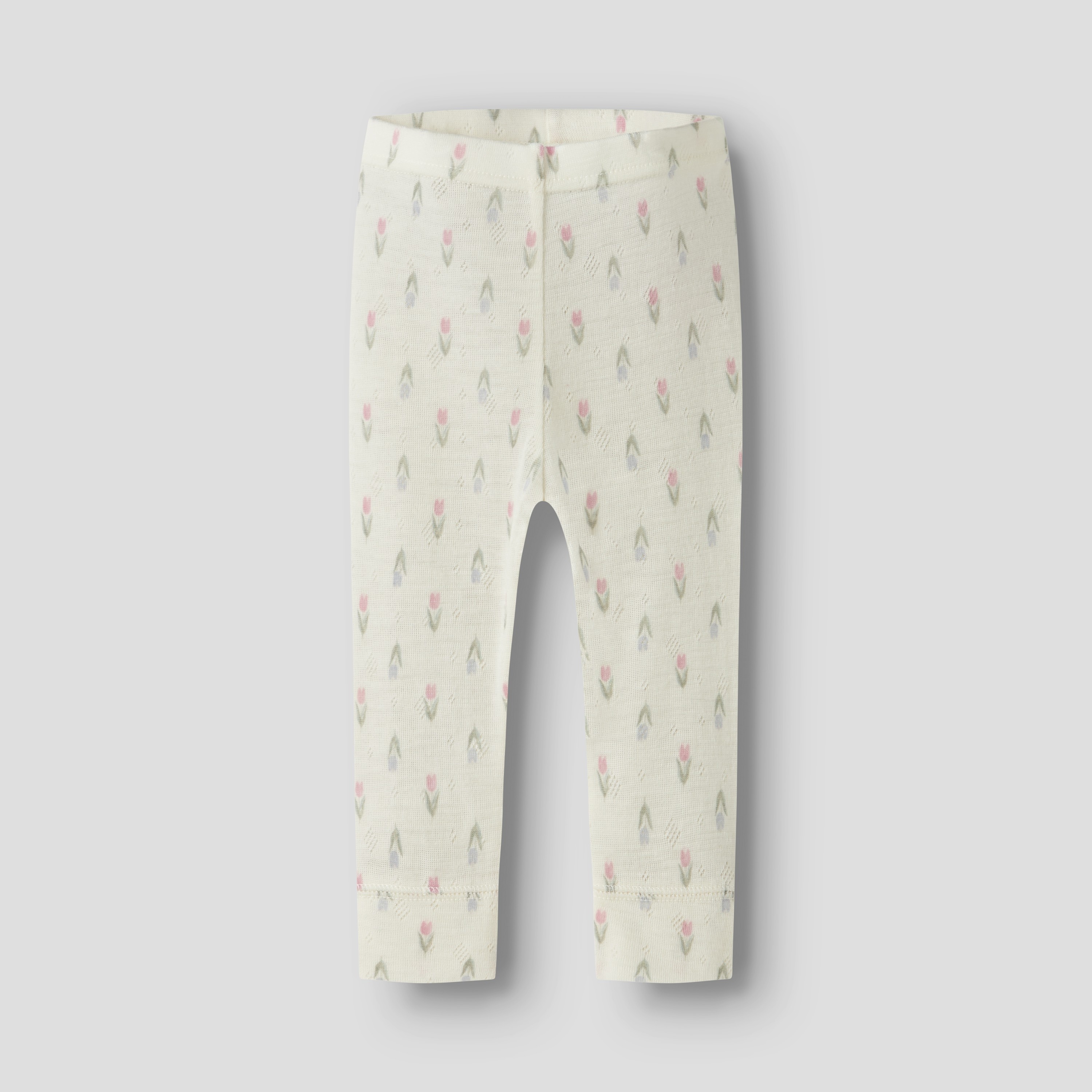 Forfra av kremhvite babybukser med et delikat rosa, blått og grønt tulipanmønster.