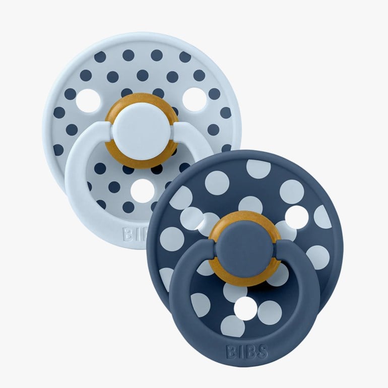 To runde babysmokker: en mørkeblå med hvite prikker, en lyseblå med mørkeblå prikker.