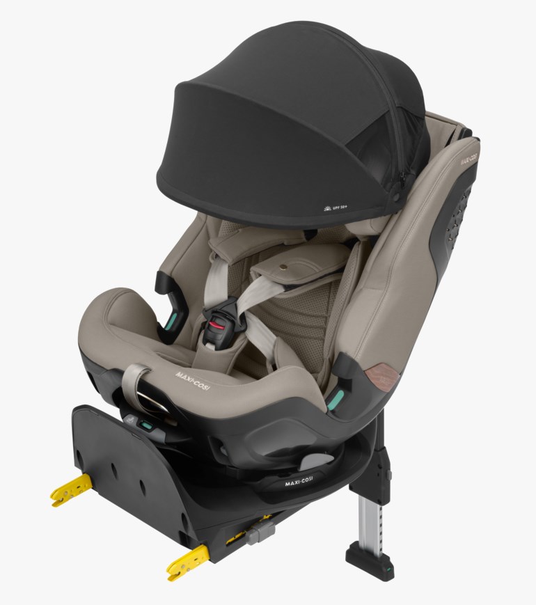 Beige babybilsete med svart solskjerm, 5-punktssele og svart base med gule ISOFIX-fester.