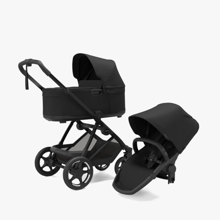 Svart barnevogn med liggedel og handlekurv, ved siden av et separat svart sittedel med kalesje.