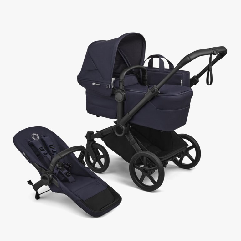 En marineblå og svart barnevogn med liggedel, ved siden av et separat småbarnsete med stropper.
