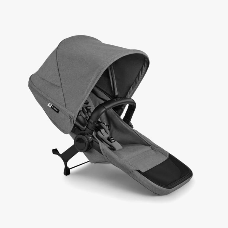 Grå og svart barnevognsete med kalesje og sele, vist i vinkel.