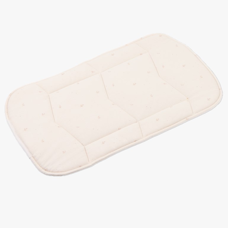 Kremhvit vattert babymadrass med avrundede hjørner og diskret bladmønster.