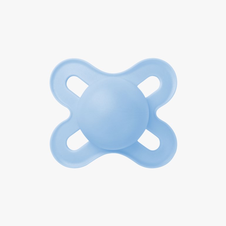 En lyseblå babysmokk, firkløverformet med en rund sentral del.