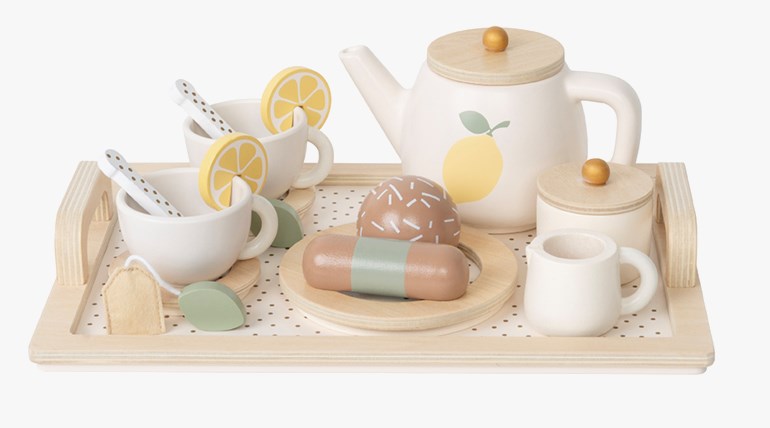 Hvitt og naturfarget treleketesett med tekanne, kopper, fat, sitron, kaker, tepose og brett.