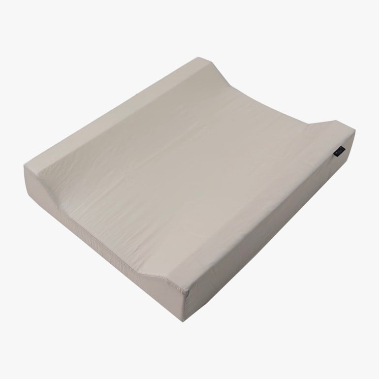 Lys beige rektangulær stellematte med hevede sider og en liten svart etikett, vinklet ovenfra.