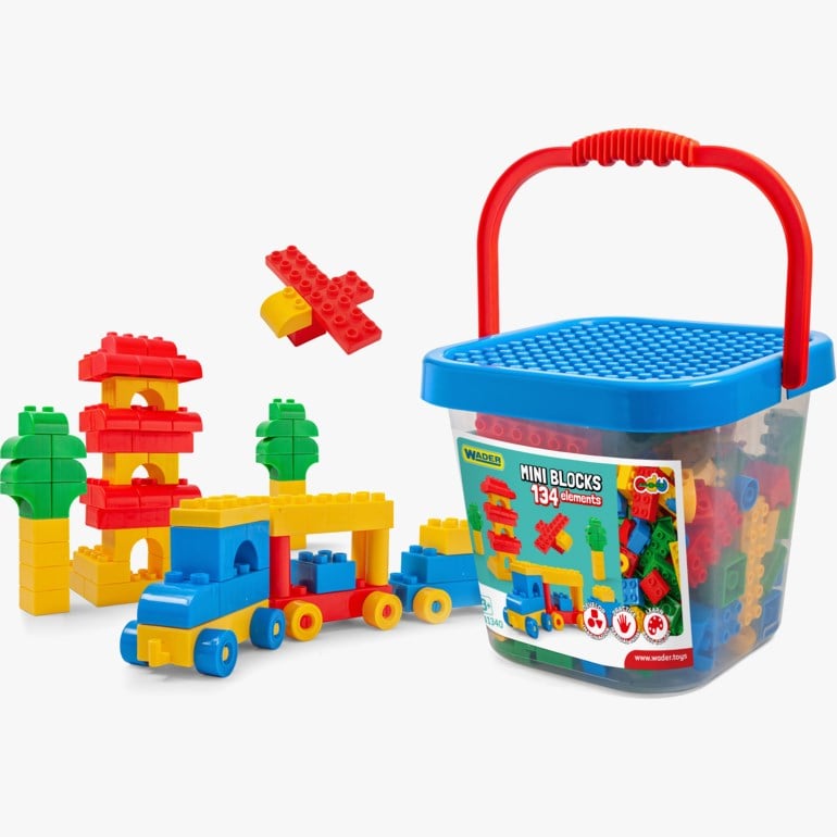 En klar plastbøtte med blått lokk, rødt håndtak, fylt med fargerike byggeklosser og ulike blokkkonstruksjoner.