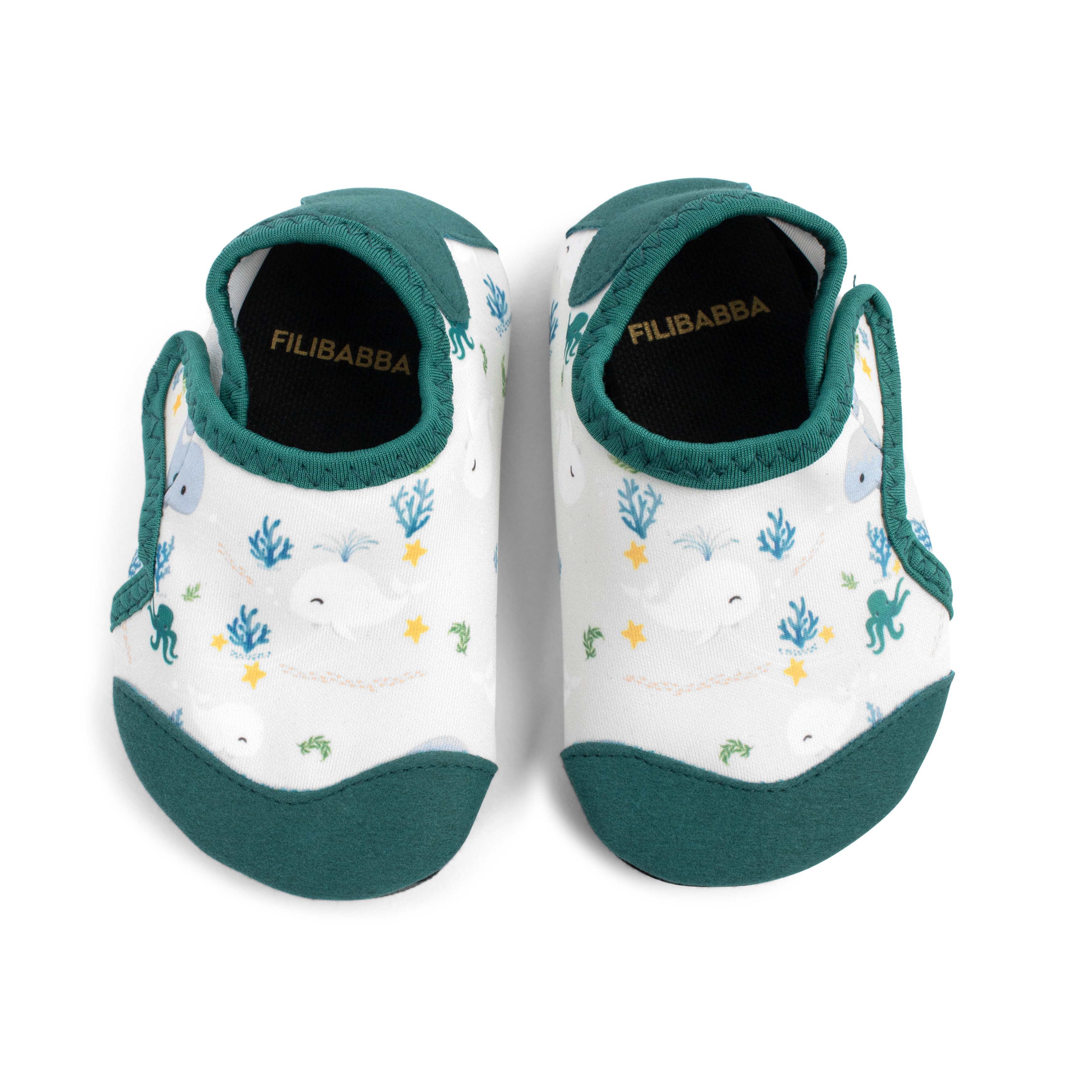 Et par hvite babysko med grønn kant og et undervannsmønster med hvaler, blekkspruter og koraller.