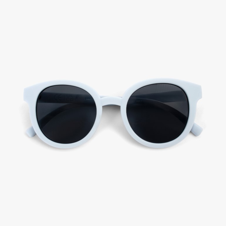 Lyseblå runde solbriller med mørke glass, sett ovenfra på en hvit bakgrunn.