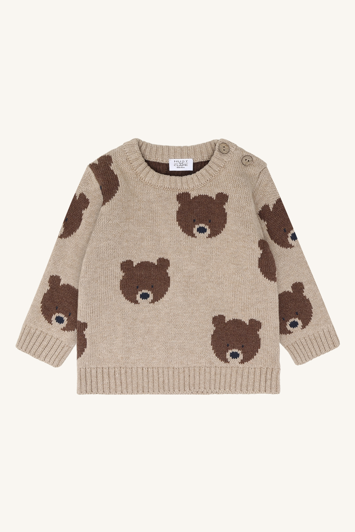 Forfra, strikket beige babysweater med mørkebrune bjørnemotiver og to knapper på skulderen.