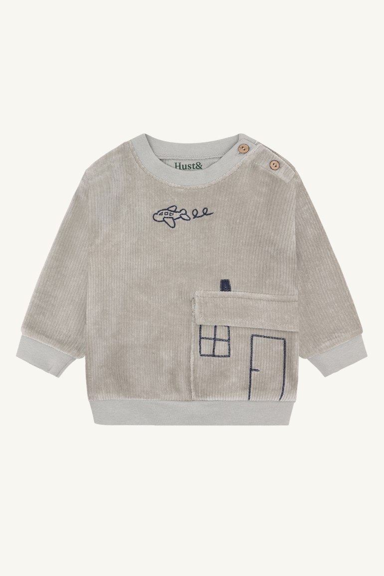 Frontutsikt av en babygenser i grå kordfløyel med skulderknapper, brodert fly og husdesign med lomme.