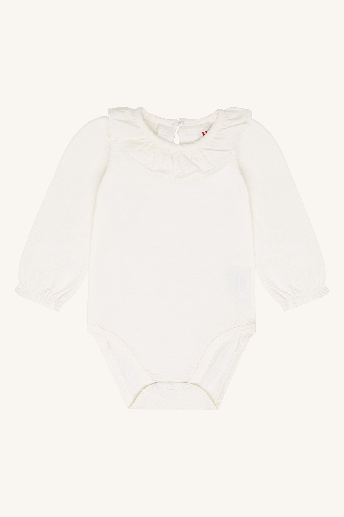 Forfra av en teksturert hvit langermet babybody med rysjekrage og trykknapplukking.