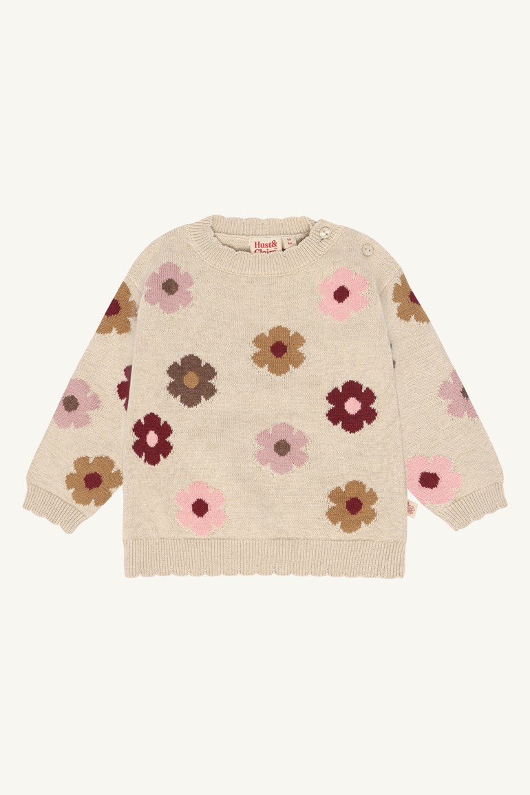 Babys beige strikkegenser med flerfargede blomstermønstre, med rund hals og skulderknapper.