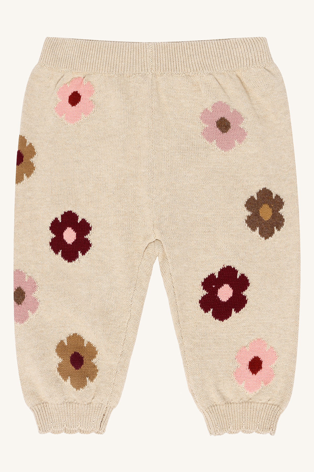 Beige strikkede babybukser med rosa, mørkerøde og brune blomstermønster, forfra.