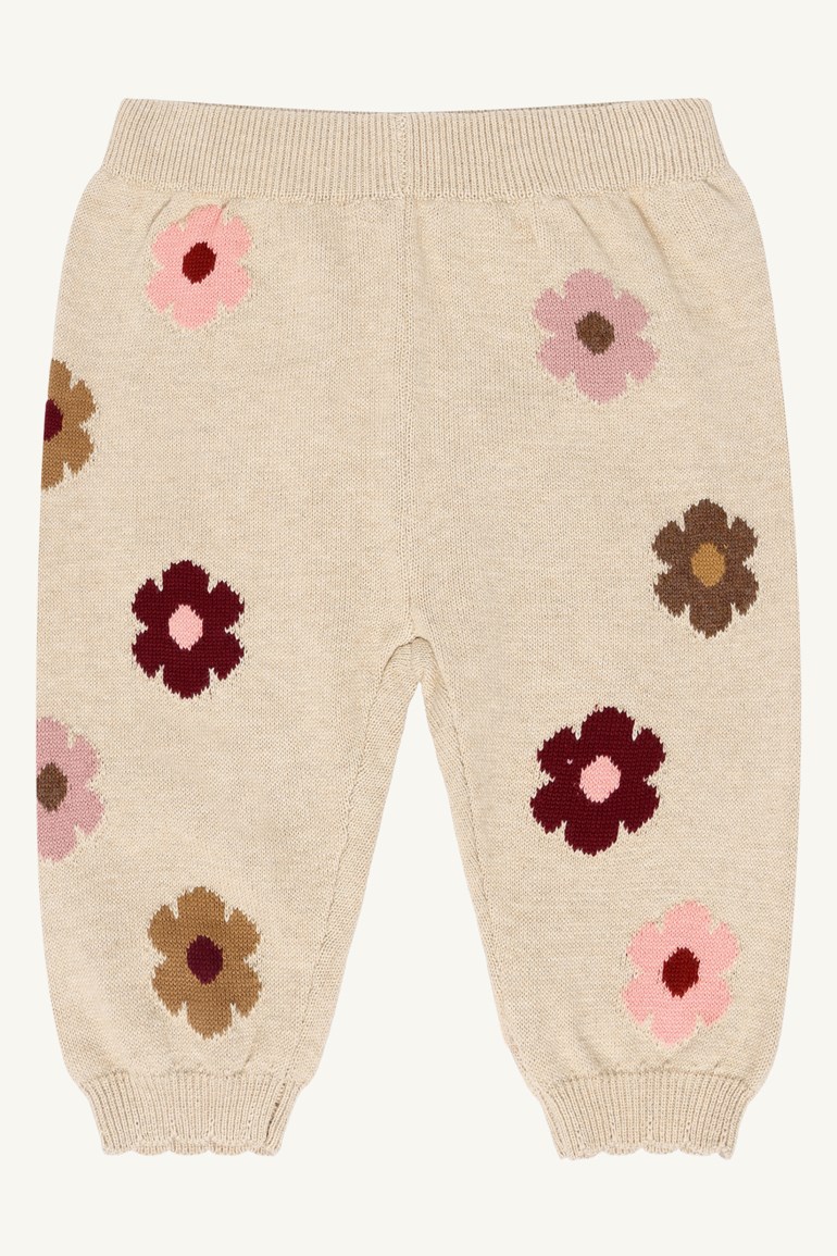 Beige strikkede babybukser med rosa, mørkerøde og brune blomstermønster, forfra.