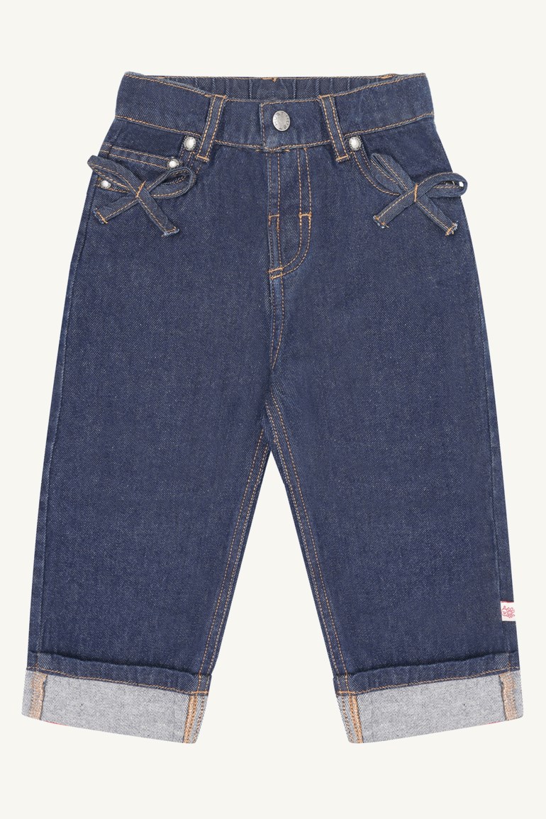 Mørkeblå barnejeans i denim med frontlommer, dekorative sløyfer og oppbrettede kanter, forfra.