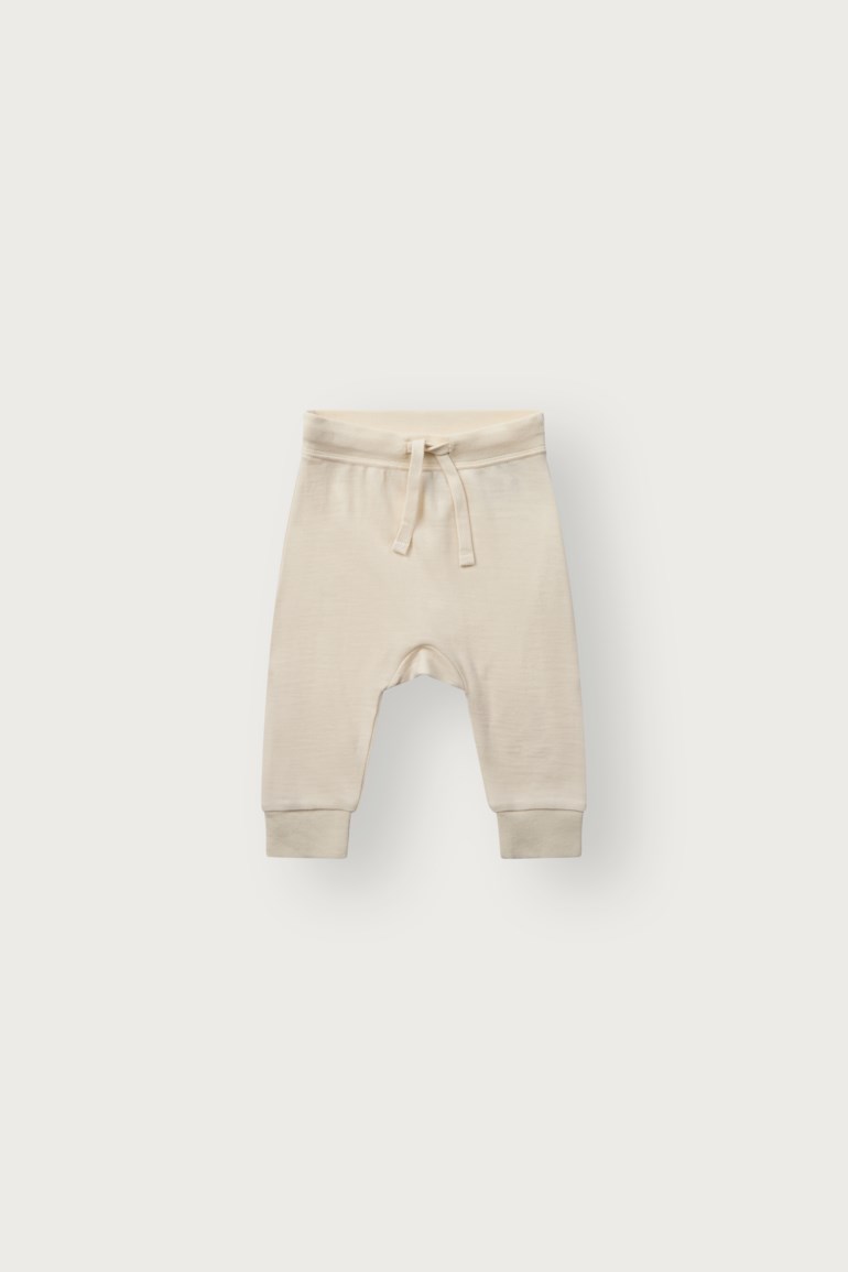 Forfra lysebeige babybukse med elastisk snøring i midjen og mansjetter ved anklene.
