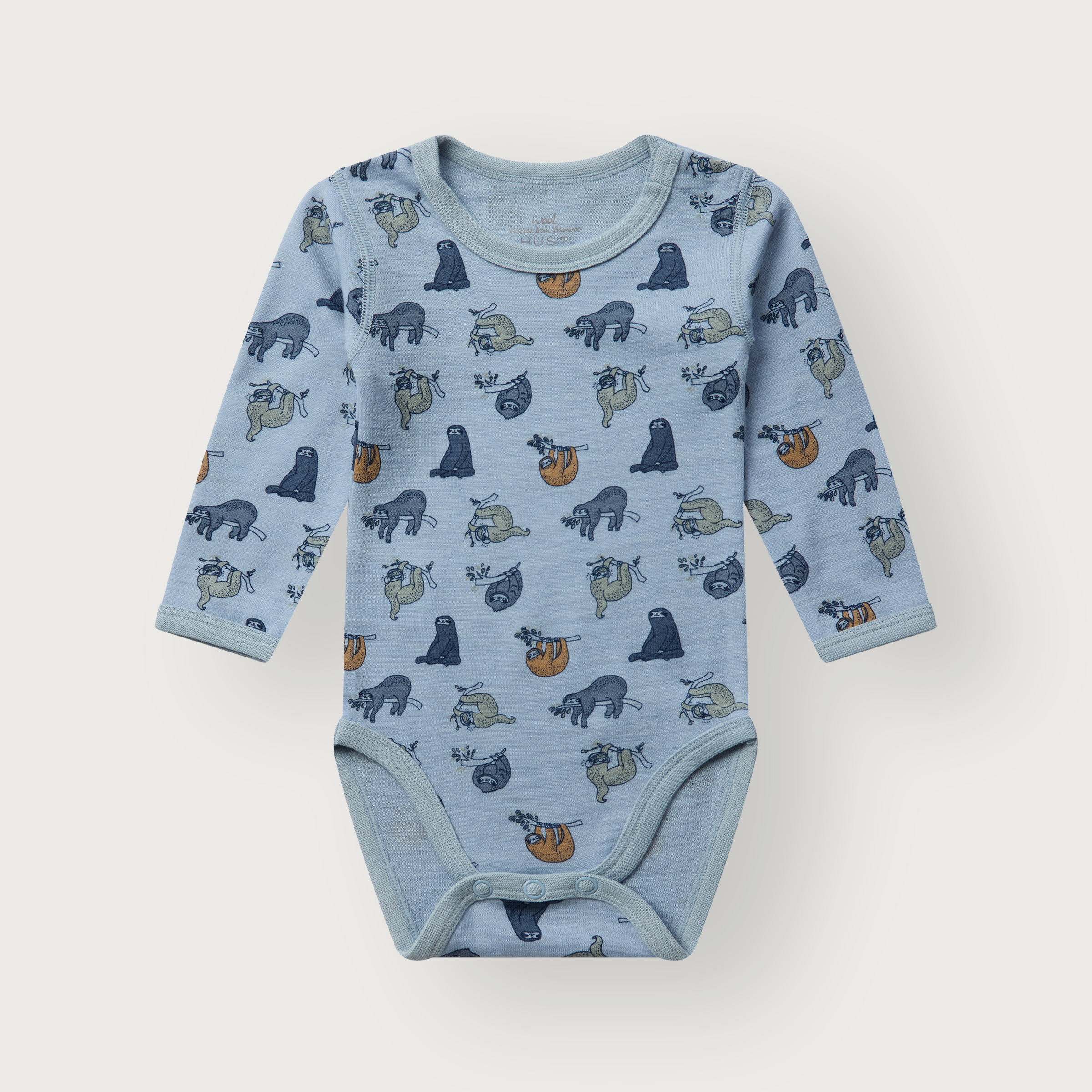 Frontvisning av en baby lys blå langermet body med heldekkende dovendyrprint og trykknapper.
