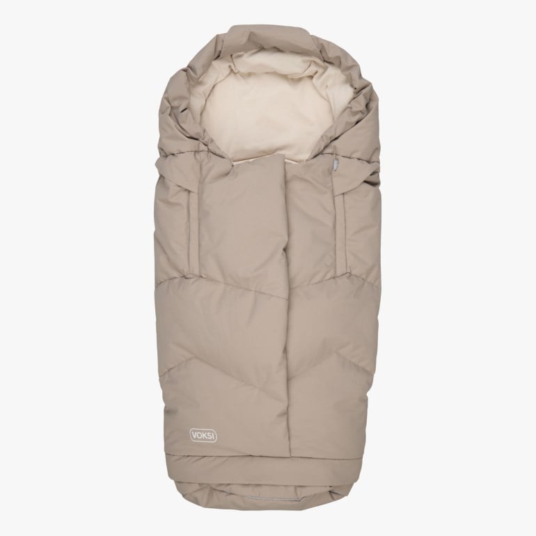 En beige vattert babyvognpose med kremfarget fôr og en Voksi-logo nederst, forfra.