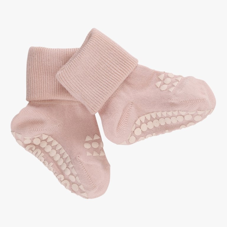 Et par rosa baby-antiskli-sokker med lyse prikker og trekanter på sålene.