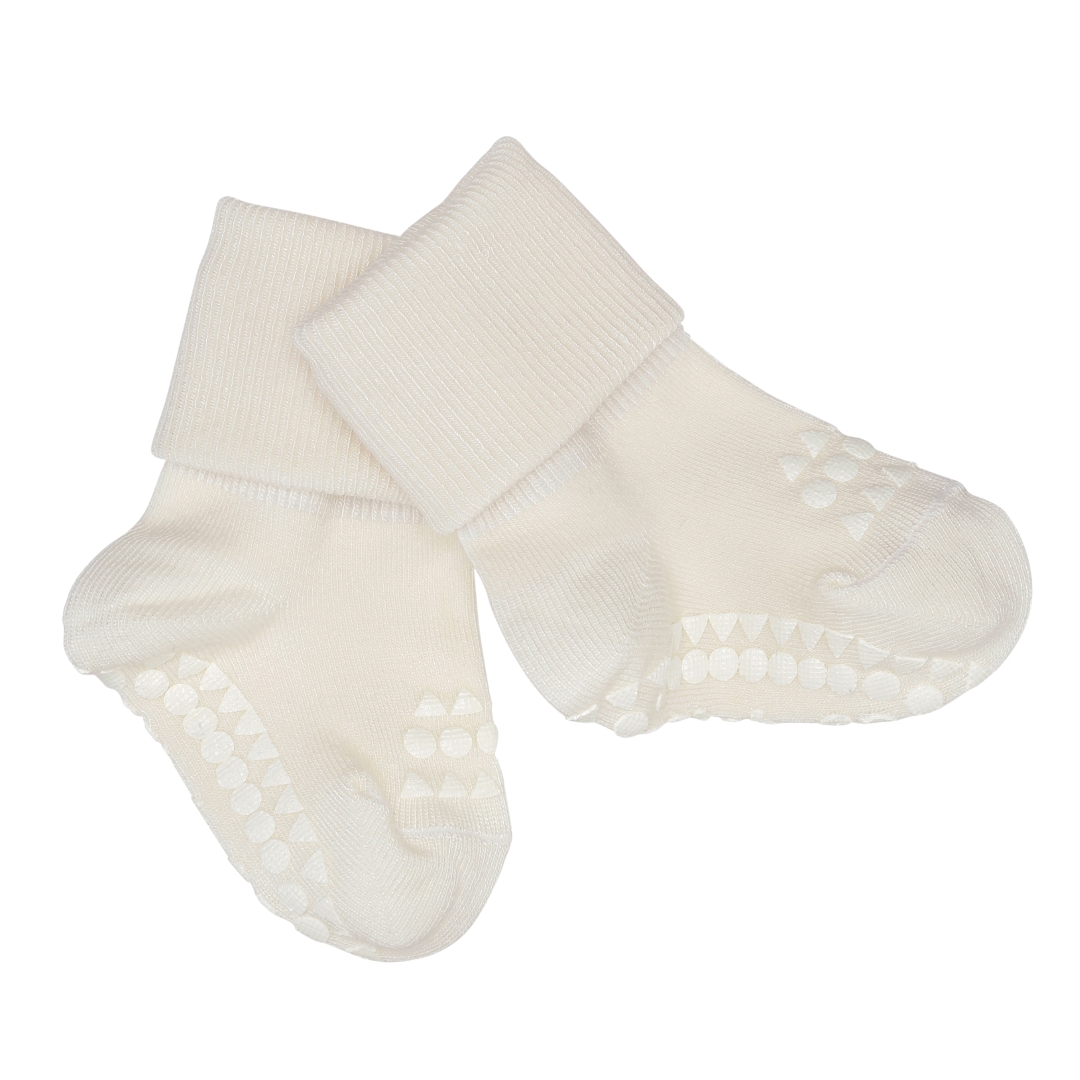 Par kremhvite baby antiskli-sokker med ribbestrikkede mansjetter og grepsmønster på sålene.