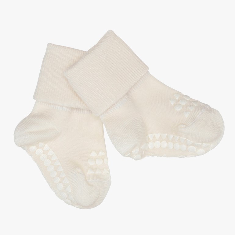 Par kremhvite baby antiskli-sokker med ribbestrikkede mansjetter og grepsmønster på sålene.