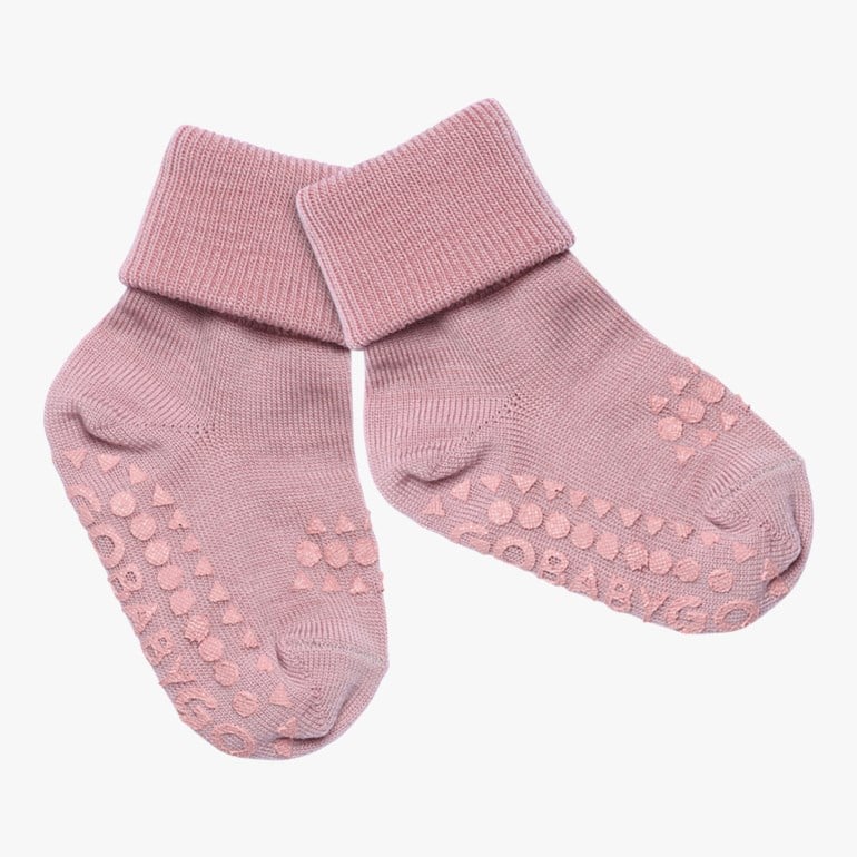 Rosa baby anti-skli sokker med ribbestrikkede nedbrettede mansjetter og antiskli-grep i sirkel-, trekant- og tekstformer.