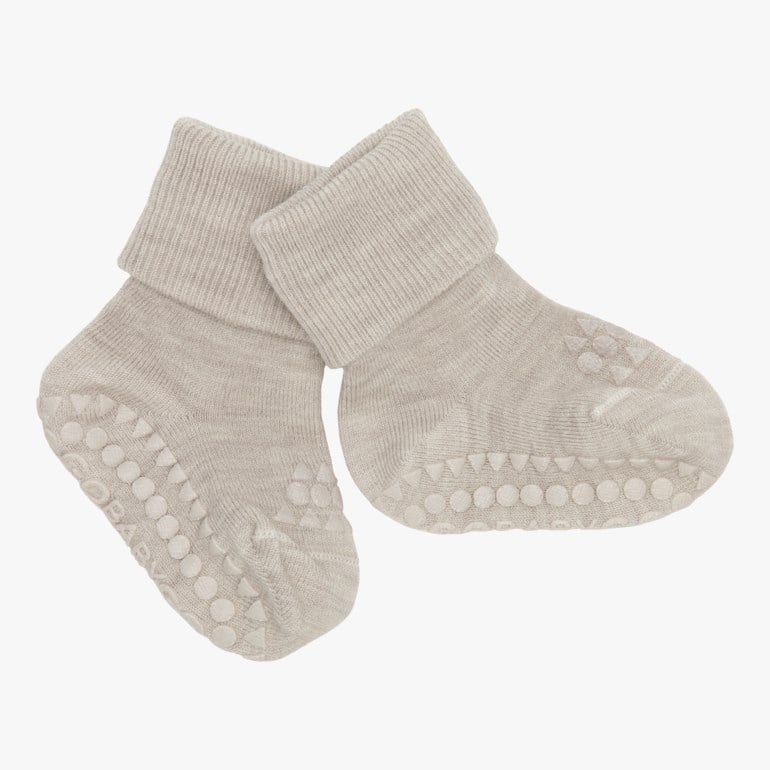 Par beige babystrømper med ribbestrikkede mansjetter og antiskli-grep på sålene.