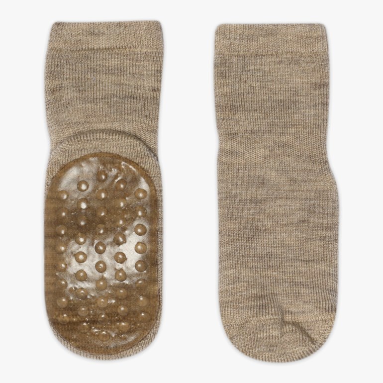 Et par beige strikkede antiskli-sokker, hvorav den ene viser silikongrep på sålen.