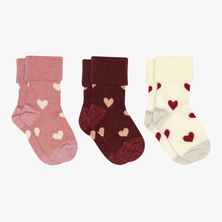 Tre par sokker for barn med brettede mansjetter: rosa med hvite hjerter, burgunder med beige hjerter og off-white med røde hjerter.