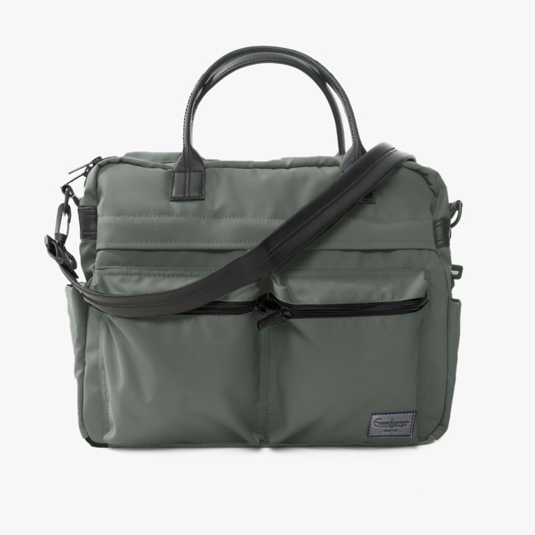 Grønn stoff skulderbag med svarte håndtak, justerbar skulderrem og glidelåslommer foran.