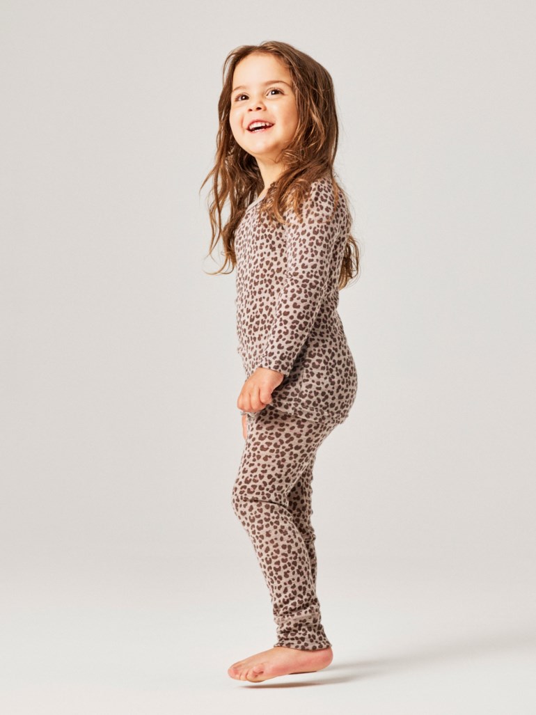 Barn har på seg et todelt beige pyjamas-sett med leopardmønster, lange ermer og lange leggings.