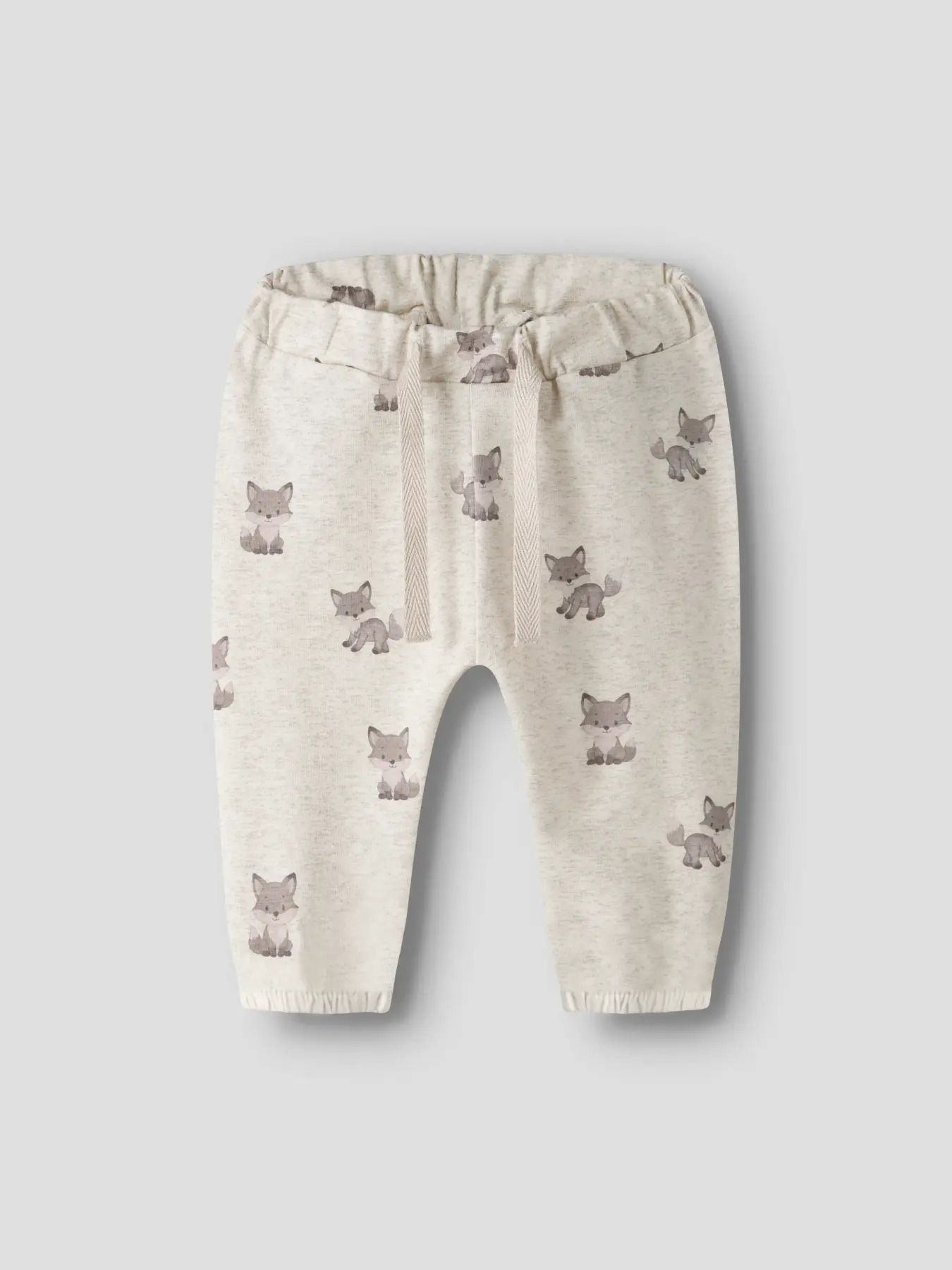 Babyens lysebeige joggebukse med revemønster, elastisk midje og fiskebenssnøring.