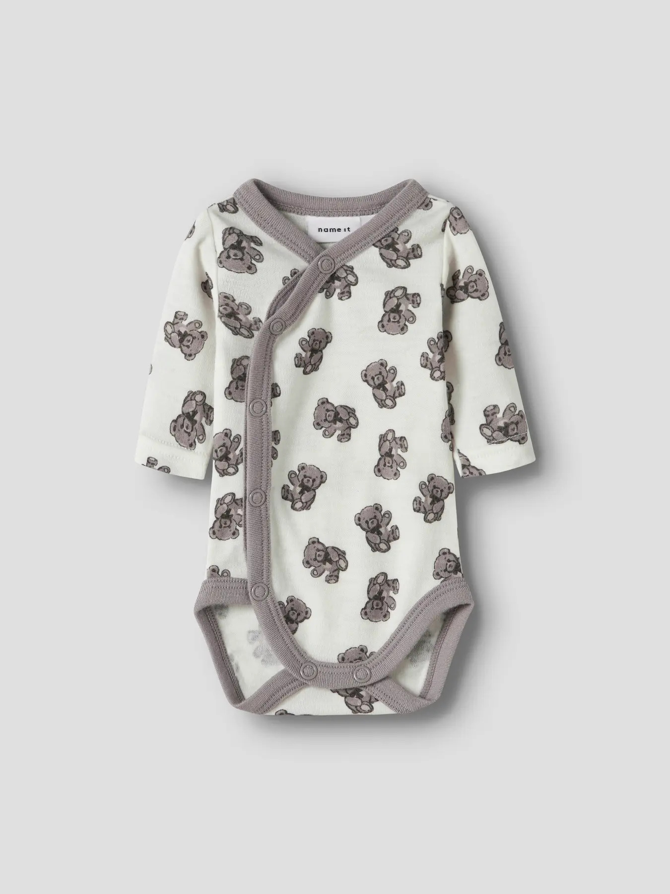 Babyens kremhvite, langermede omslagsbody med grått teddybjørnmønster og trykknapper.