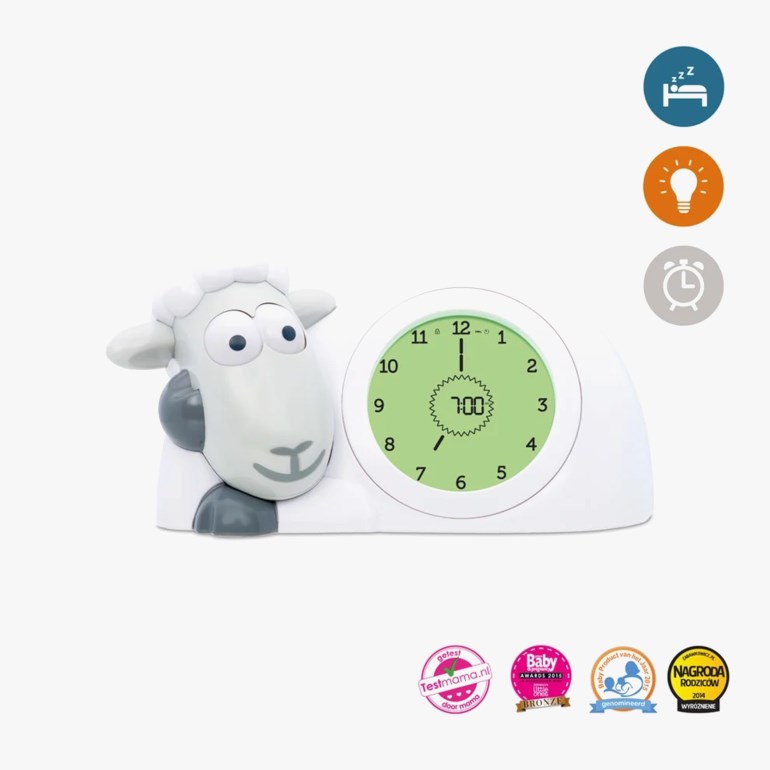 Hvit og grå sauformet digital vekkerklokke med grønn skjerm som viser 7:00 og en analog urskive.