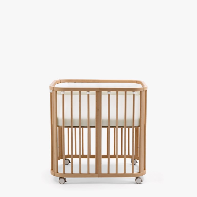 Babyseng i naturlig tre med avrundede kanter, hvite nettingvegger, en hvit madrass og grå hjul.