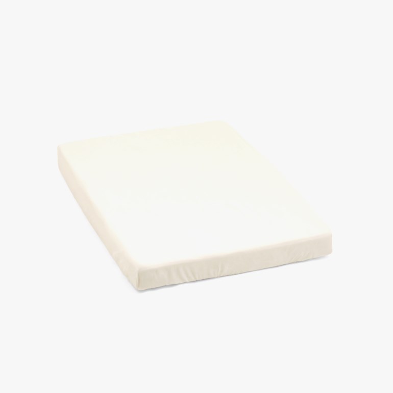 Off-white rektangulær babymadrass med mykt stofftrekk.