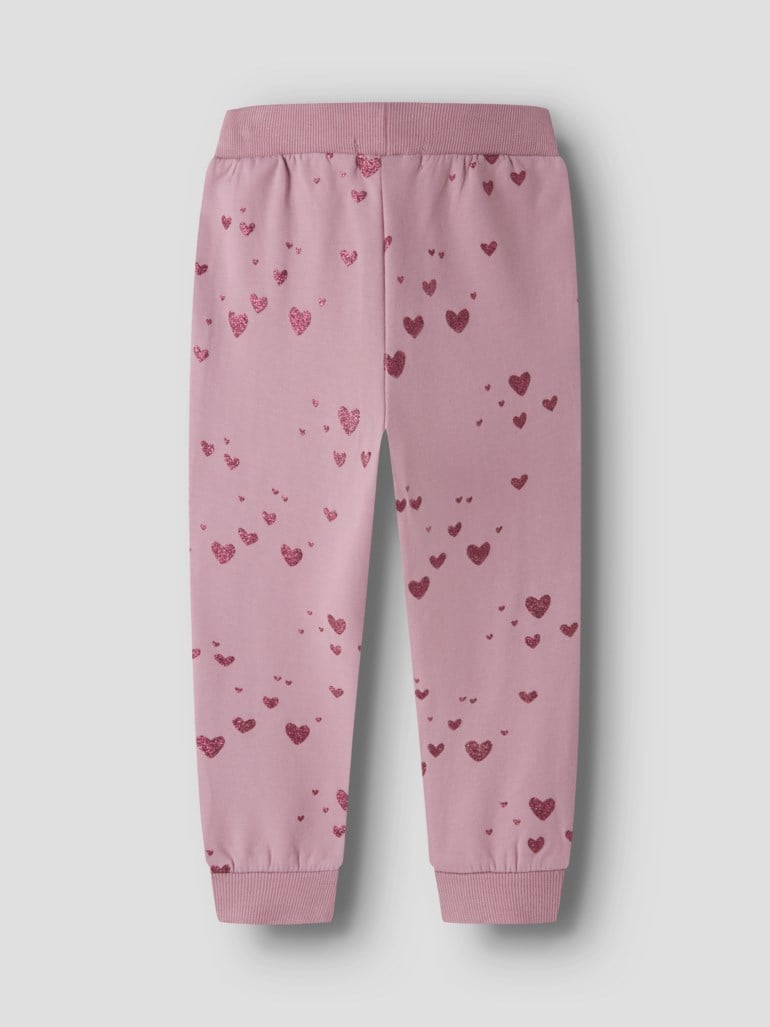 Barns rosa joggebukse med heldekkende glitrende hjertemønster, elastisk linning og ribbestrikkede mansjetter, forfra.