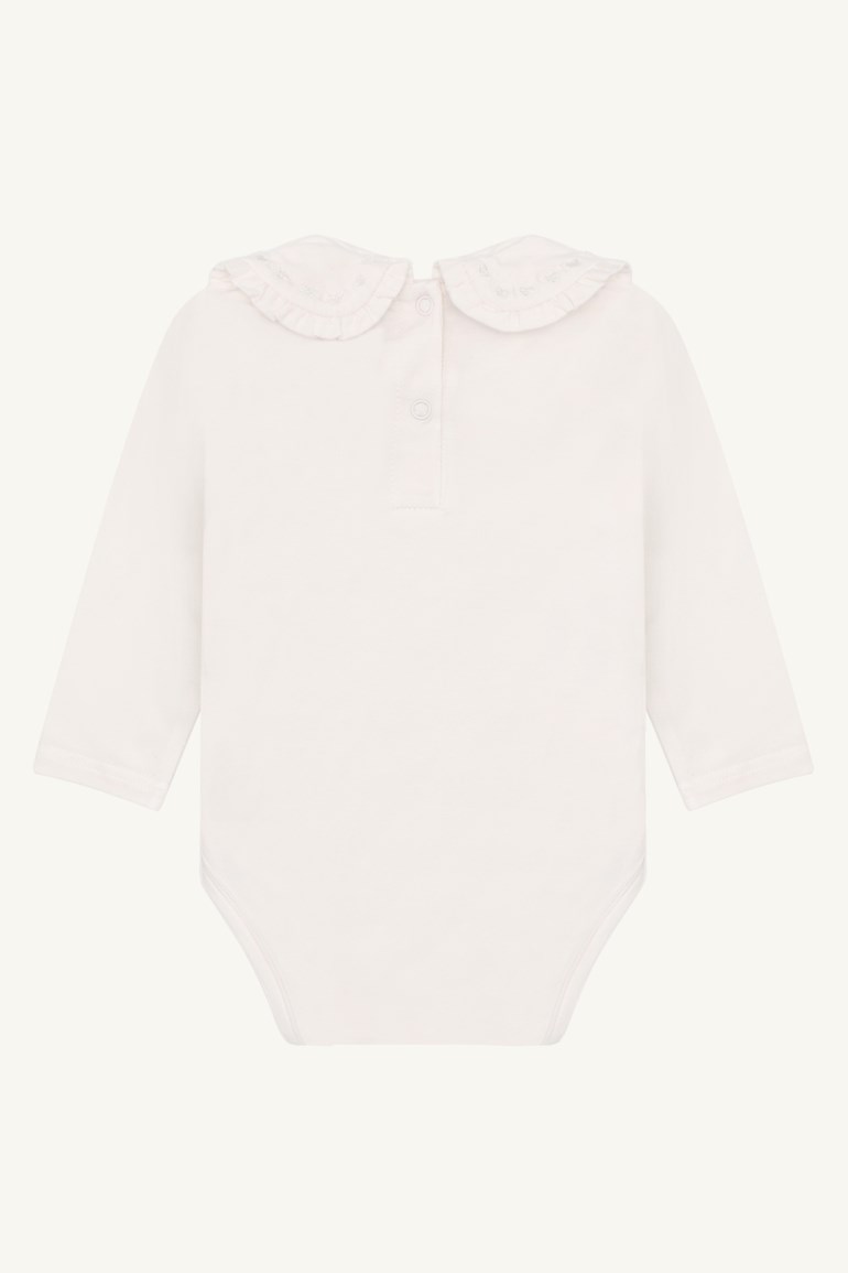 Bakfra, en lys off-white langermet babybody med rynket, brodert Peter Pan-krage og trykknapper i nakken.