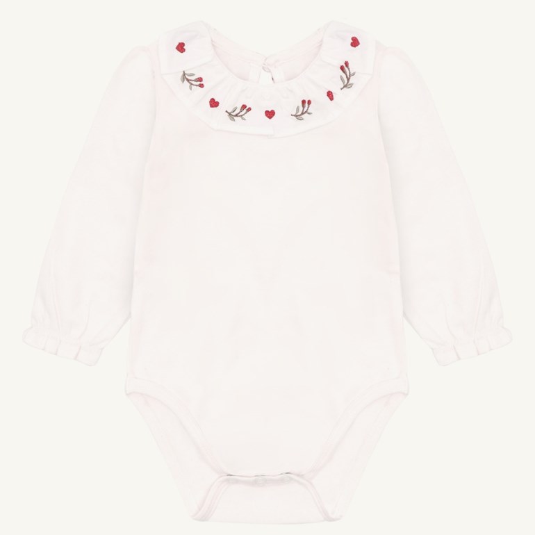 Hvit babybody med lange ermer og en volangkrage brodert med røde hjerter og grønne kvister.