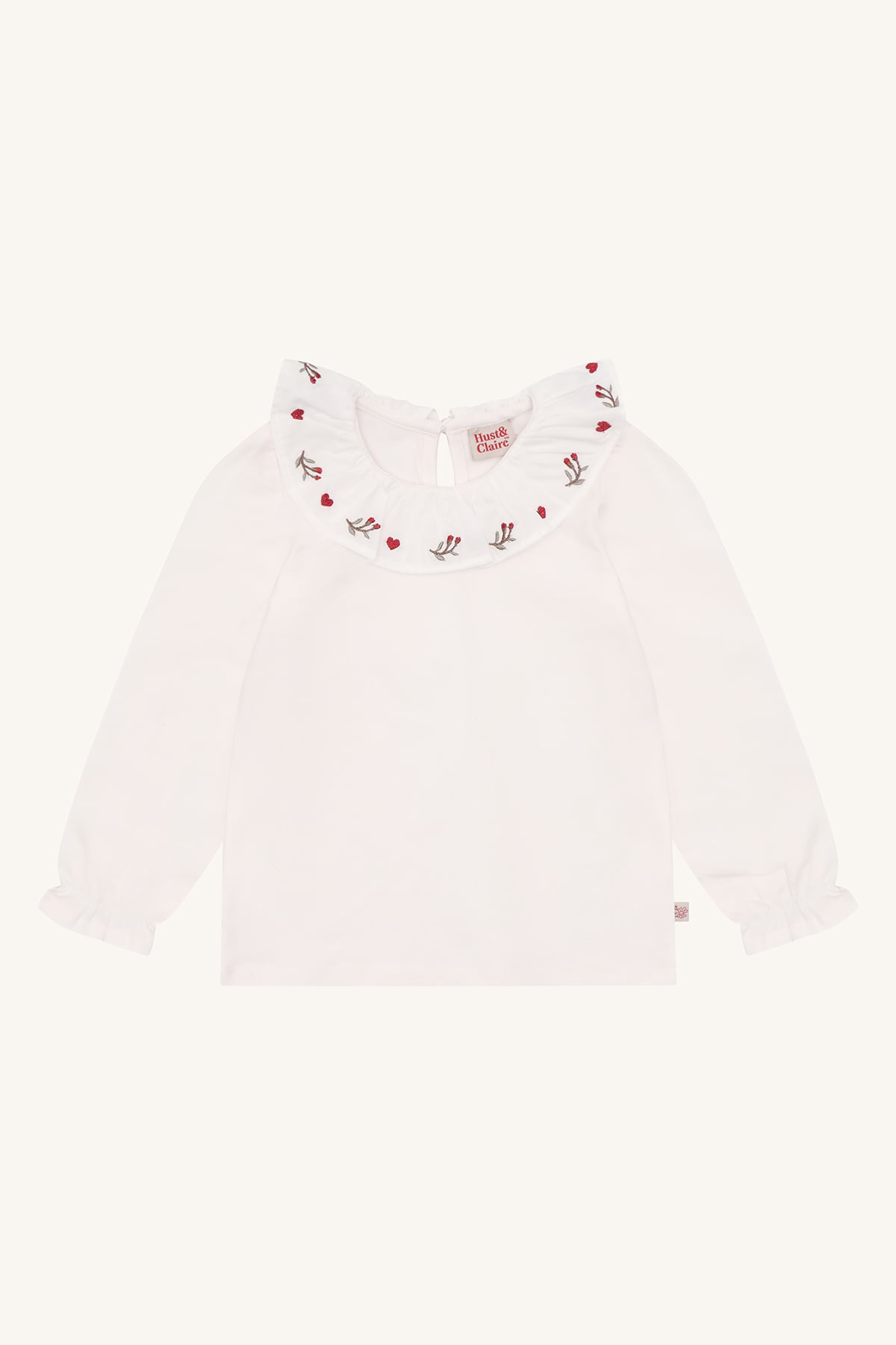 Hvit langermet barnetopp med volangkrave brodert med røde hjerter og blomstermotiver, og volangmansjetter.