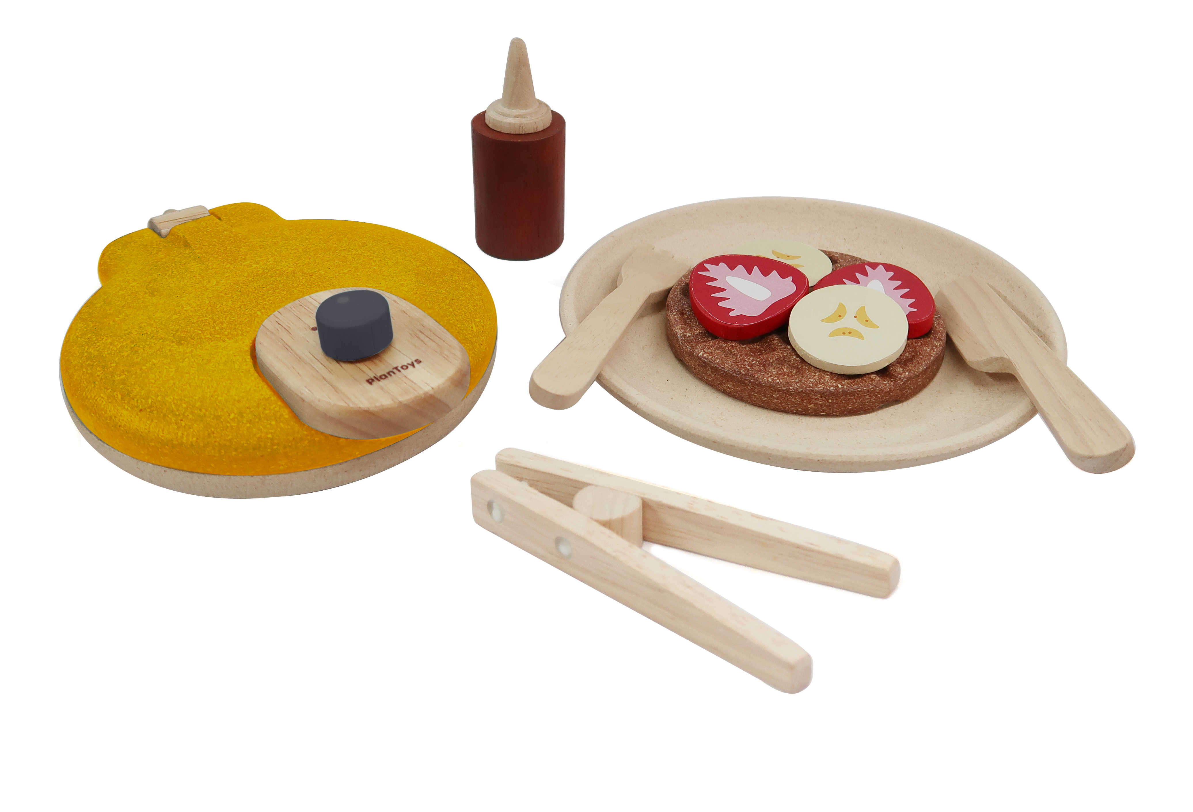 Leketøyfrokostsett i tre: pannekake på tallerken med frukttilbehør, tang, sirupsflaske og en gul pannekakemaskin.
