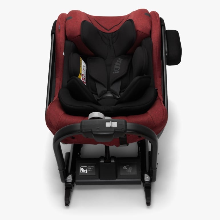 Rød bilstol med svart polstring, synlig sele og justerbar anti-rebound-bøyle foran, sett ovenfra.