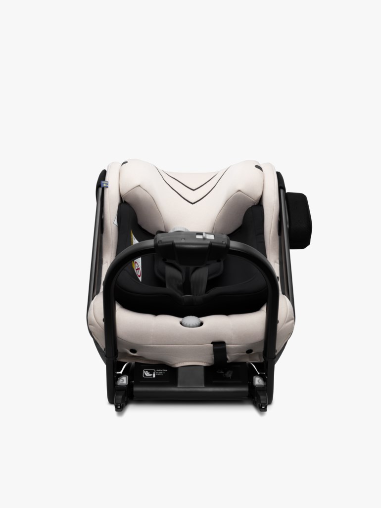 Off-white og svart baby bilbarnstol med sikkerhetssele, bærehåndtak og hjulunderstell, forfra.