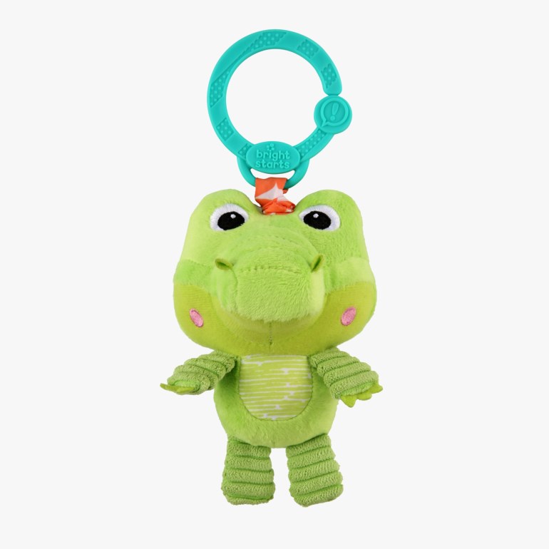 Grønn plysj krokodilleleke med stripet mage, rosa kinn, svarte øyne og en turkis plastklemme.